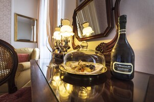 Un tavolo da pranzo con una bottiglia di vino Ca' Bertaudo, un decanter di vetro e un piatto coperto con cibo.