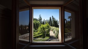 Habitación con un ventanal grande que ofrece vistas a un jardín ajardinado con árboles y un sendero.