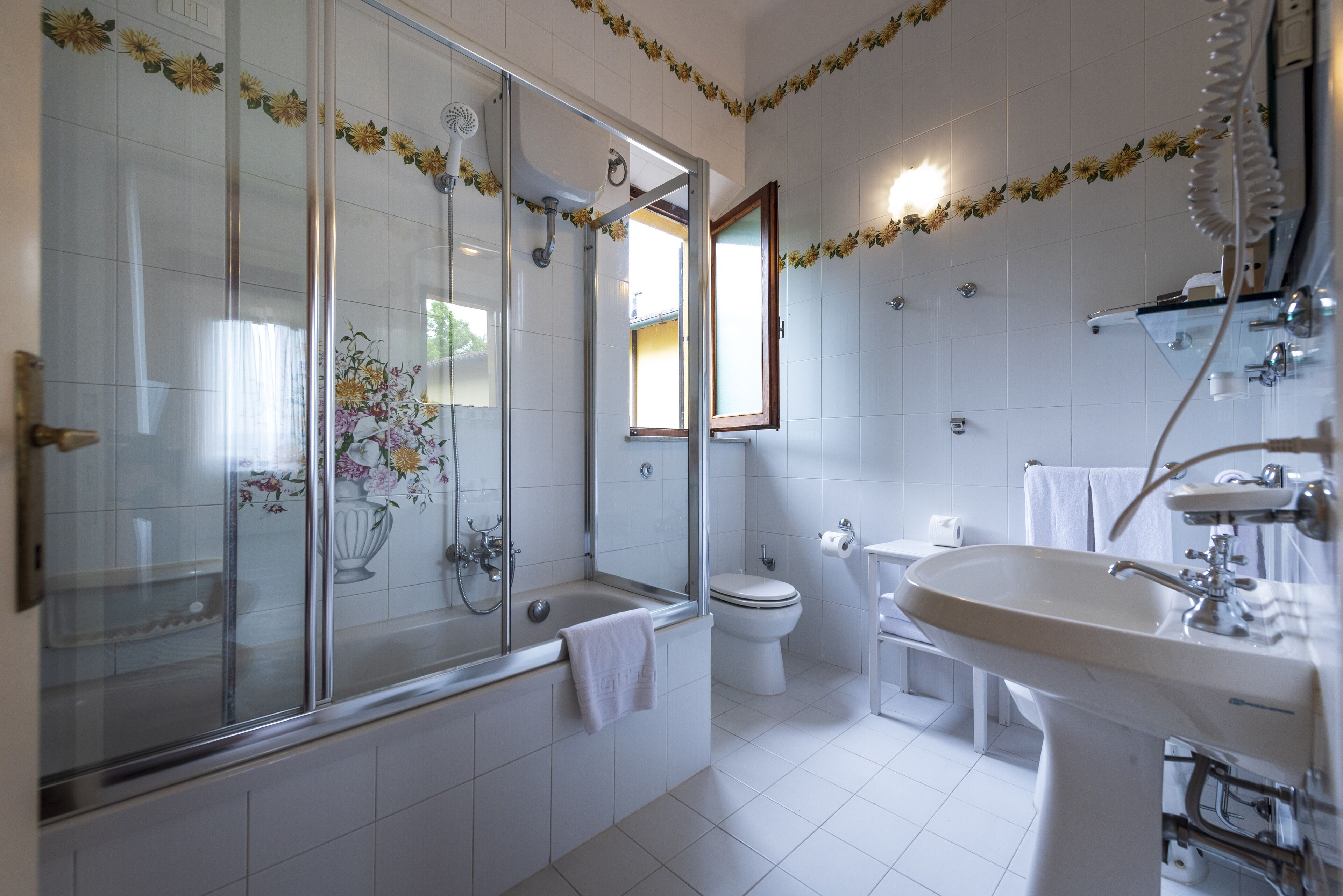 Un baño moderno con ducha de mampara de vidrio, inodoro y lavamanos.