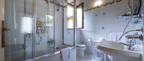 Un baño moderno con ducha de mampara de vidrio, inodoro y lavamanos.