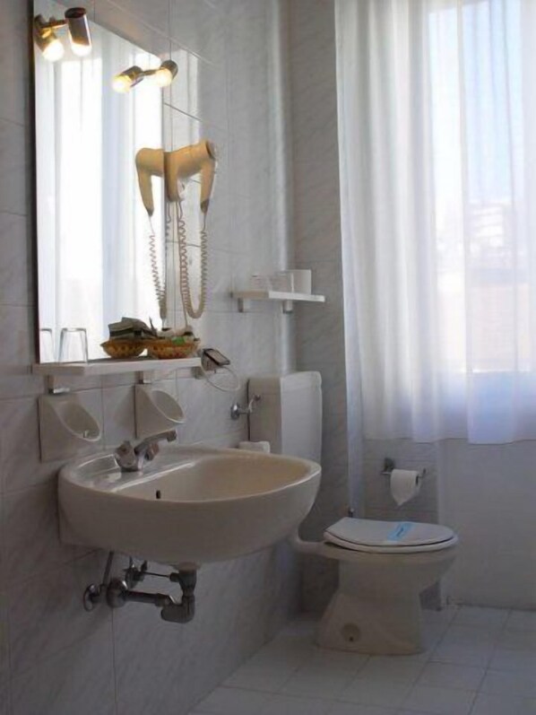 A bathroom with a sink, toilet, and a mirror with lights.