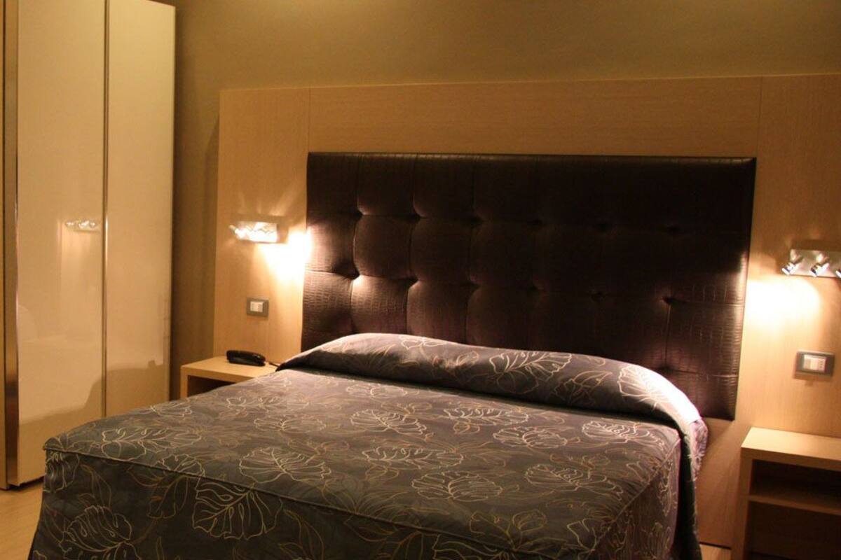 A bedroom with a bed, bedside tables, a wardrobe, and a bench.