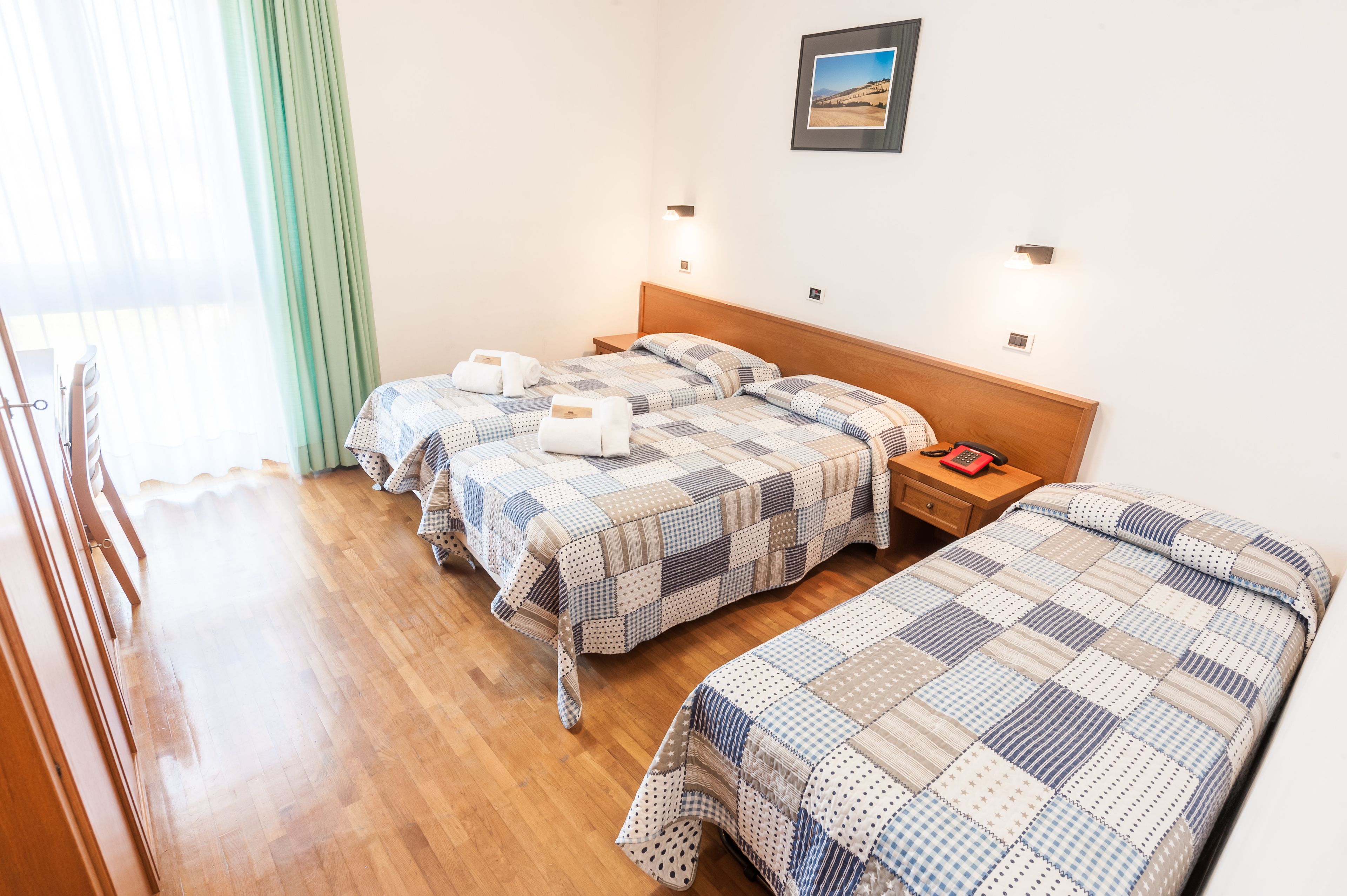 Een hotelkamer met twee bedden, een houten hoofdbord, nachtkastjes, en een lijst met een foto aan de muur.