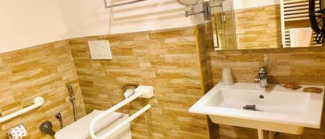 A modern bathroom with a toilet, bidet, sink, and two mirrors.