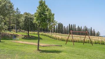 A grassy area with a swing set and a bench.