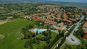 An aerial view of a town with a central square, a swimming pool, and surrounding residential buildings. - Palazzuolo (San Quirico d'Orcia)