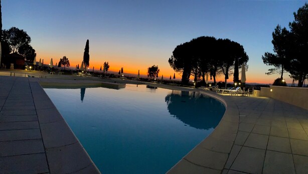 An infinity pool with a clear view of the sunset, surrounded by trees and lounge chairs. - Palazzuolo (San Quirico d'Orcia)