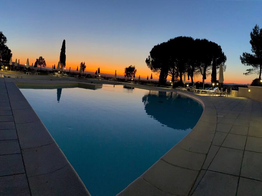 Una piscina al aire libre, una piscina con cascada, sombrillas