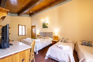 Ein Hotelzimmer mit zwei Betten, einem Schreibtisch mit Fernseher und einer Holzbalkendecke.