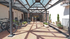 A covered outdoor area with a glass roof, bicycles parked, and potted plants. - Palazzuolo (San Quirico d'Orcia)