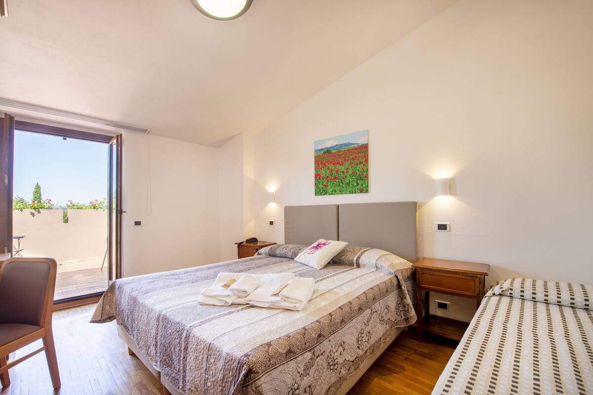 Un dormitorio con cama, una silla, una mesita de noche y un cuadro en la pared.