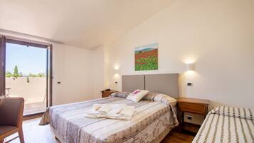 Ein Schlafzimmer mit Bett, Stuhl, Nachttisch und einem Bild an der Wand.