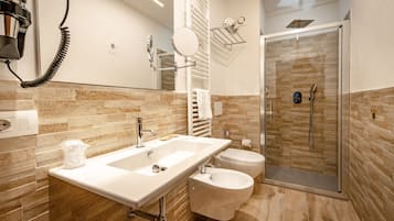 Un baño moderno con un lavamanos grande, inodoro, bidé y una ducha a ras de suelo.