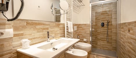 Un baño moderno con un lavamanos grande, inodoro, bidé y una ducha a ras de suelo.