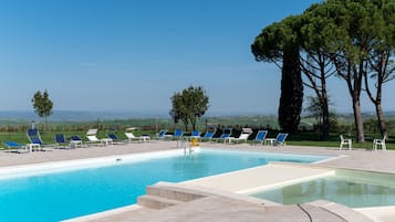 Una piscina al aire libre, una piscina con cascada, sombrillas