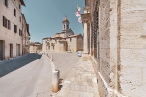 Eine ruhige Straße mit historischen Gebäuden, einer Kirche mit Glockenturm und Kopfsteinpflaster.