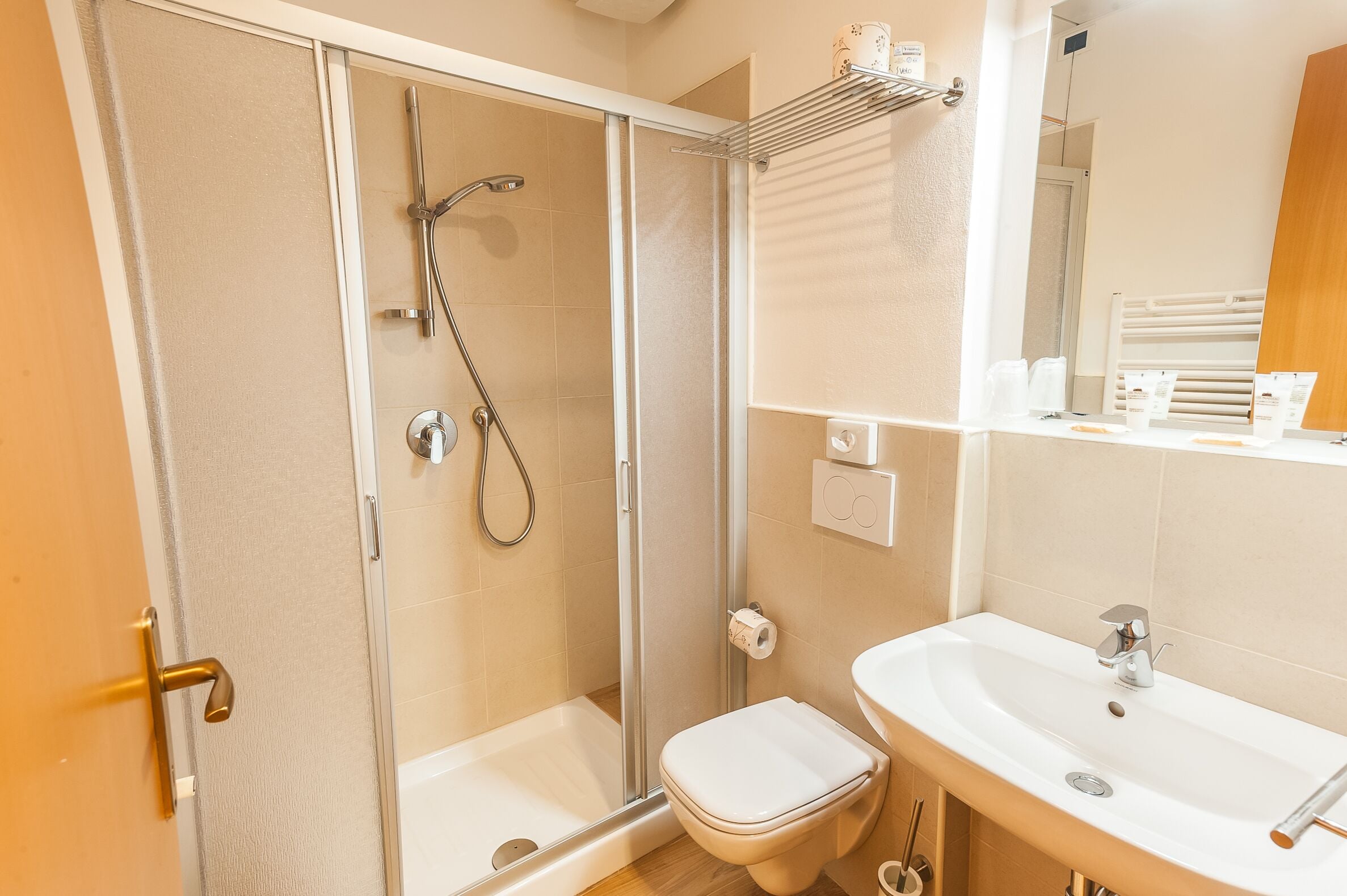 Une salle de bain avec une douche à parois de verre, des toilettes et un lavabo.