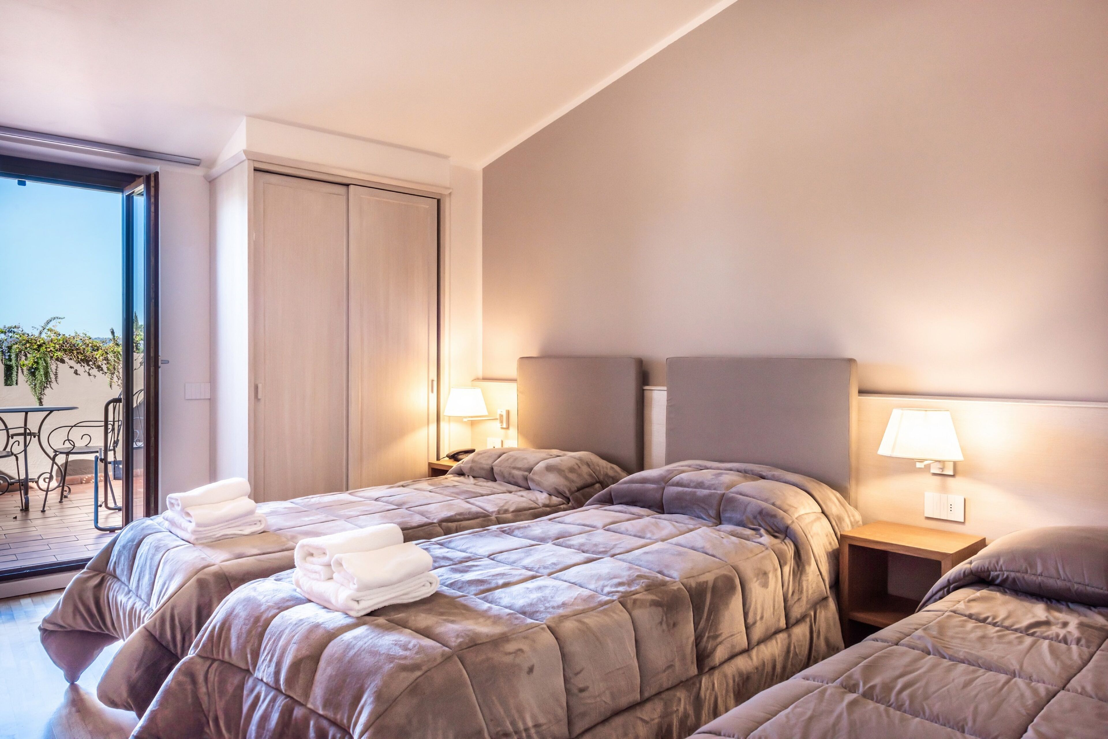 Hotellihuone, jossa on kaksi sänkyä, parveke ja näkymä ulos.