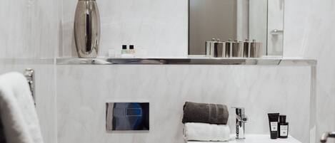 Uma casa de banho moderna com uma pia branca, um espelho e um porta-toalhas.