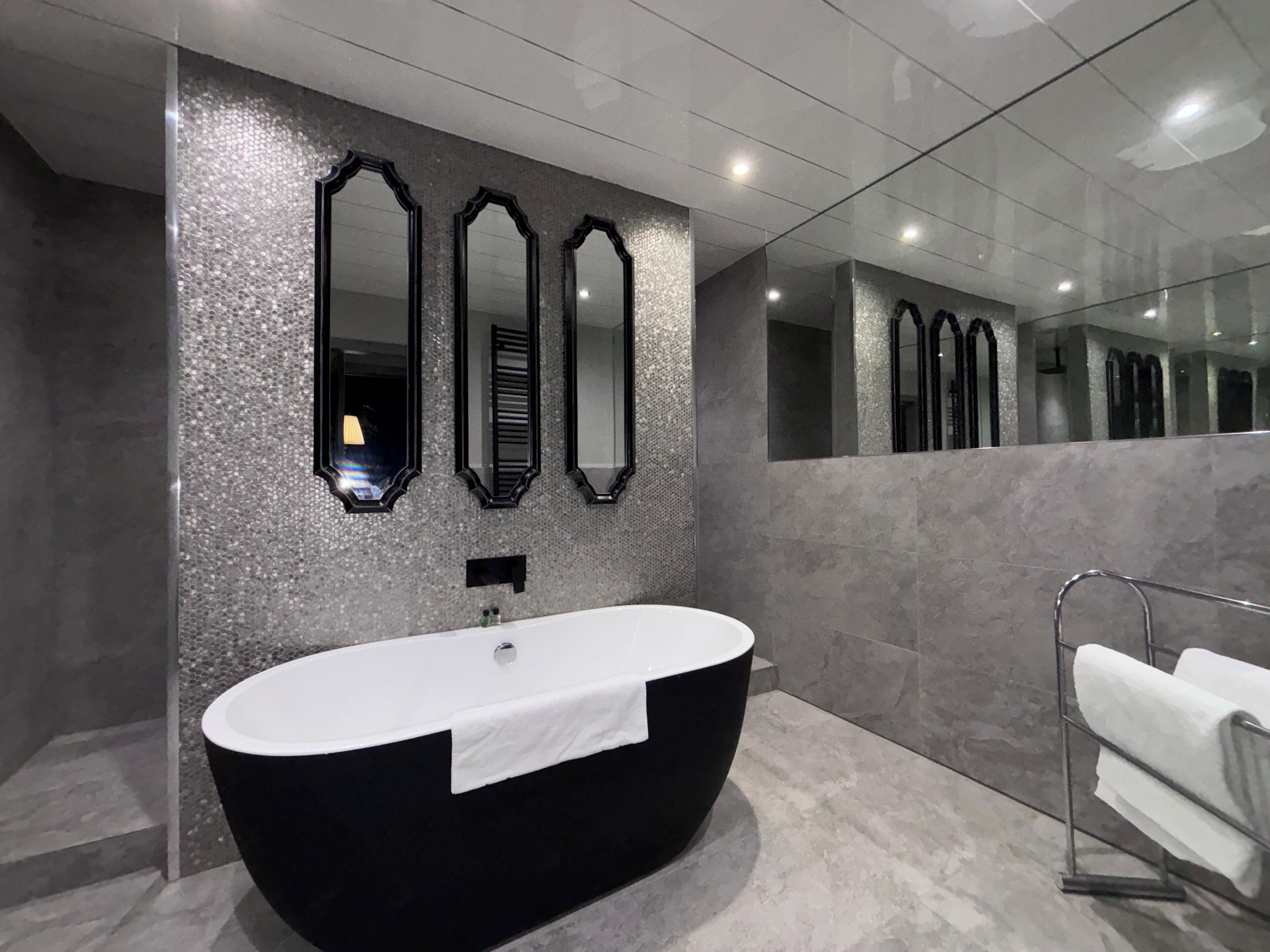 Une salle de bain moderne avec une baignoire sur pieds, un grand miroir et un porte-serviettes.