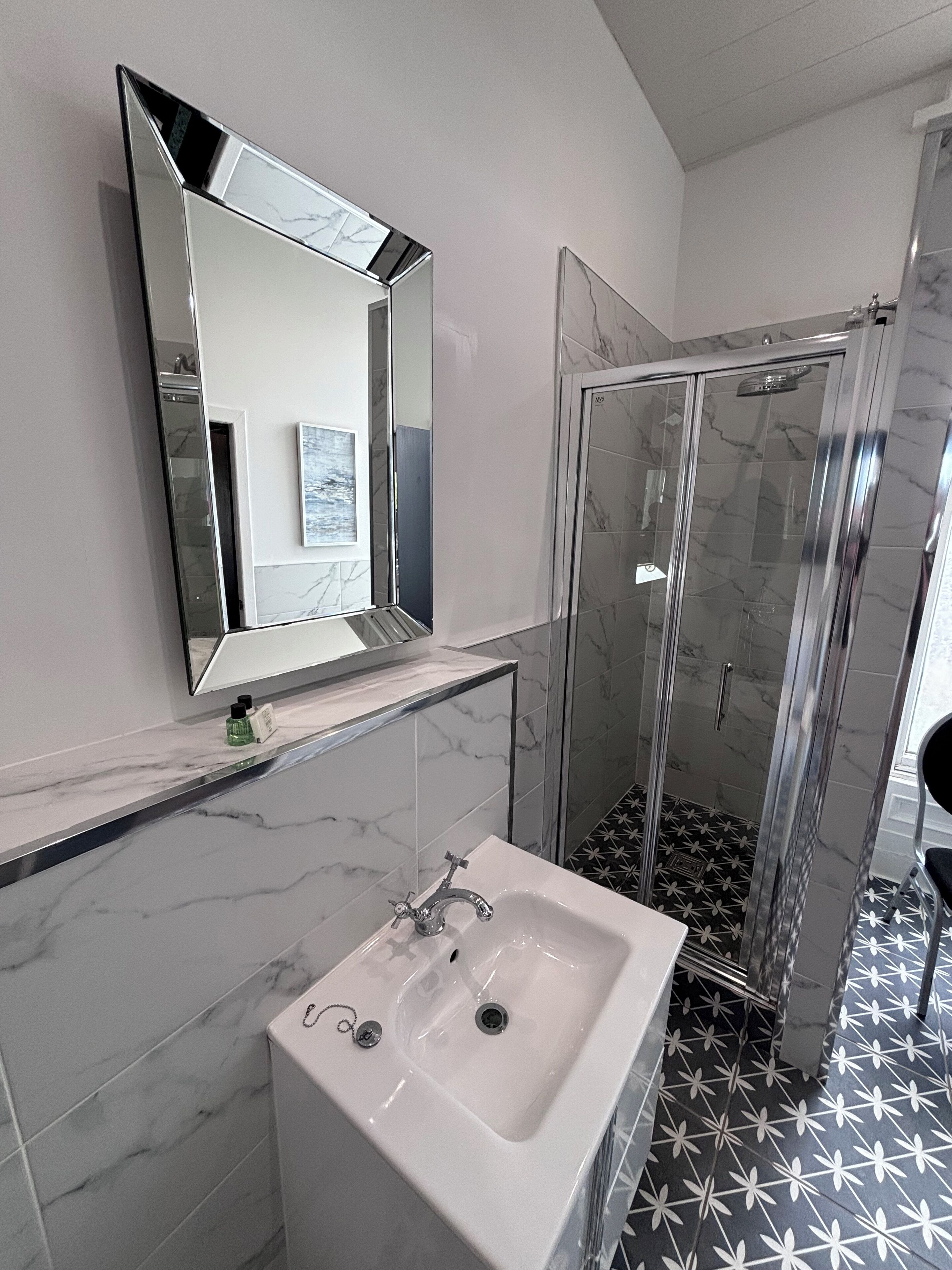 A bathroom with a white sink, a mirror, and a glass-enclosed shower.