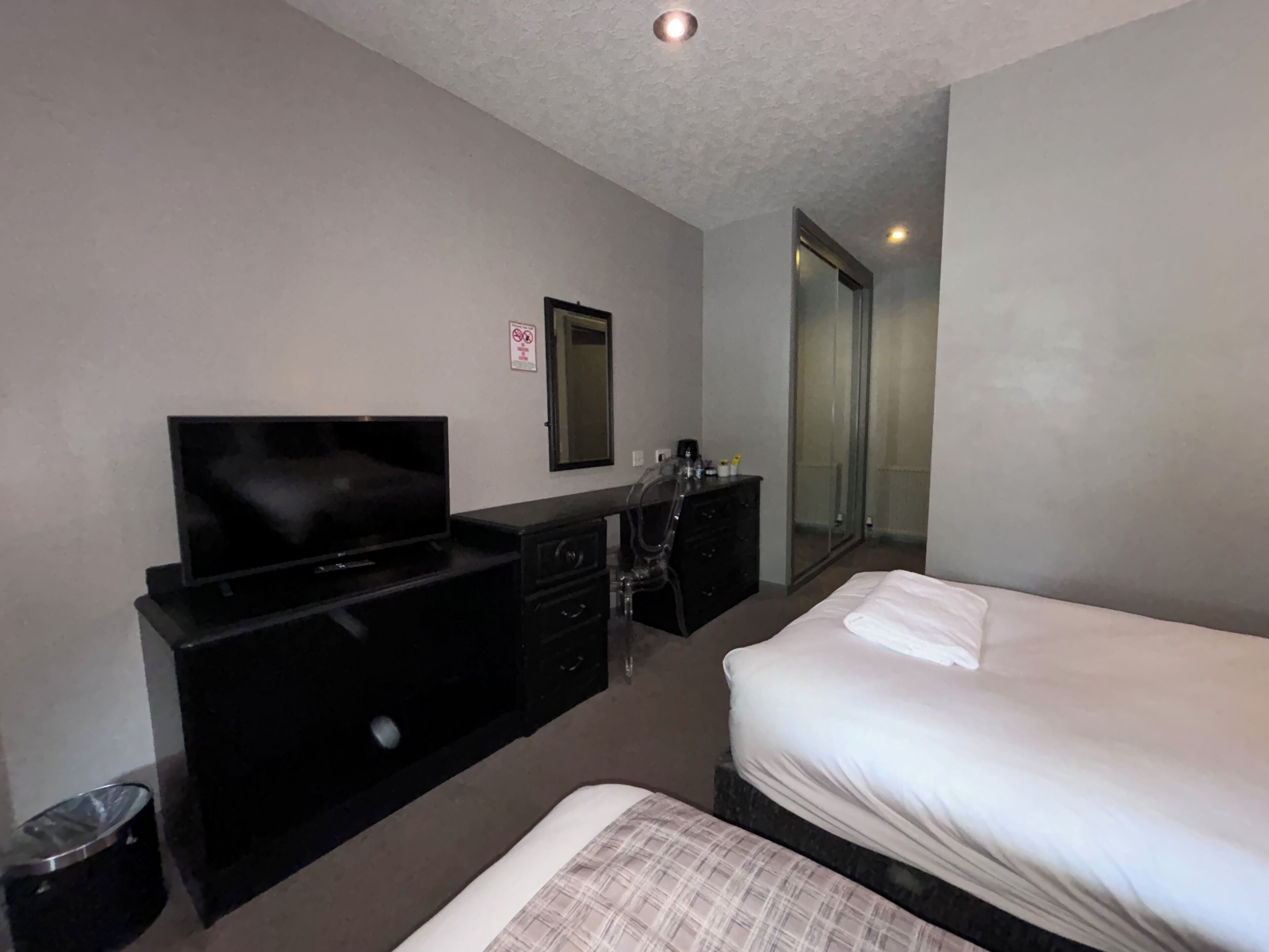 Una habitación de hotel con cama, televisión, escritorio y espejo.