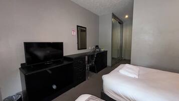 Una habitación de hotel con cama, televisión, escritorio y espejo.