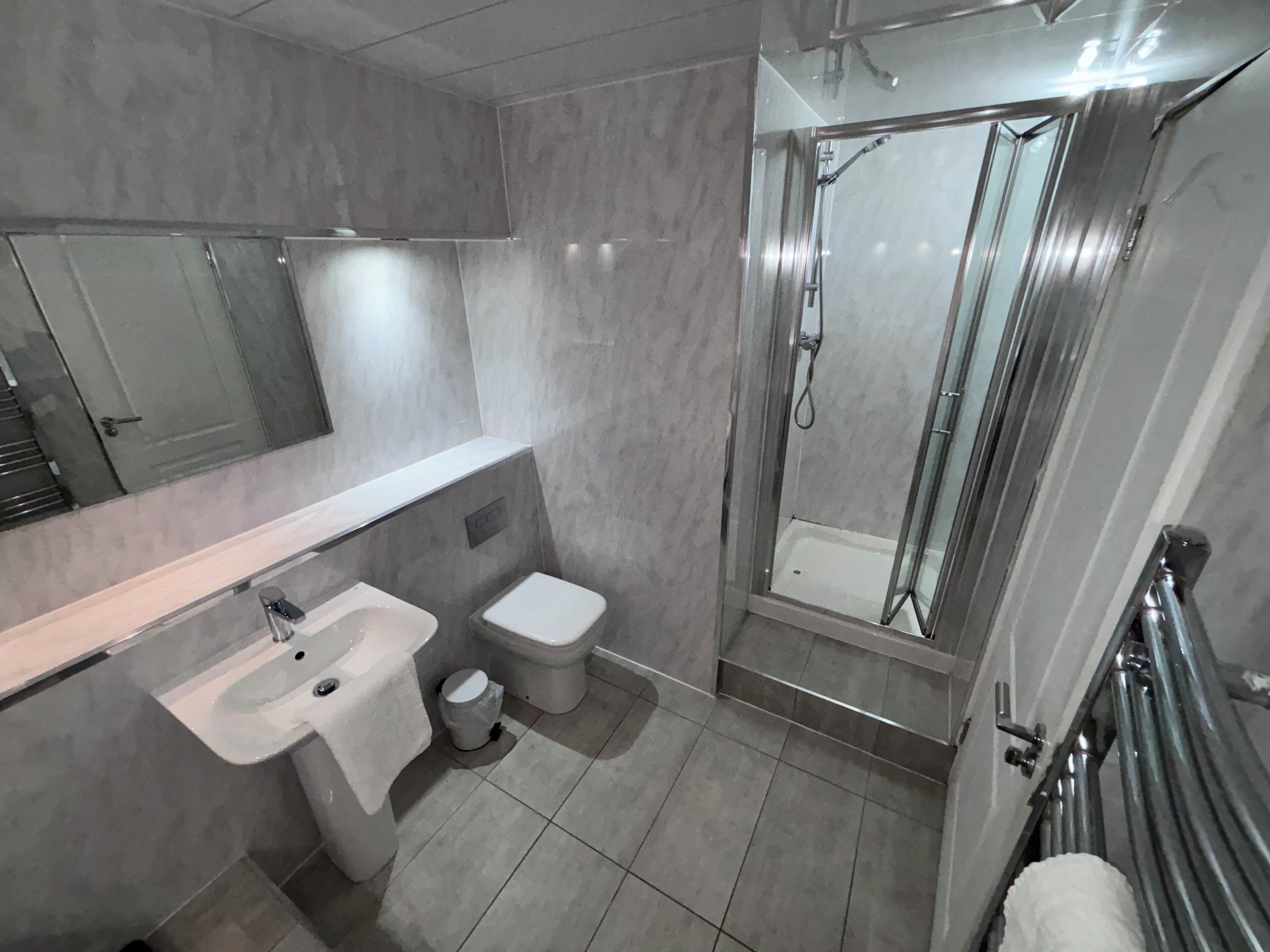 A modern bathroom with a sink, toilet, and glass-enclosed shower.