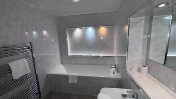 Un baño moderno con ducha envuelta en vidrio, un espejo grande y un perchero para toallas.