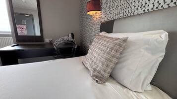 Ein Hotelzimmer mit Bett, Nachttisch, Lampe und Spiegel.