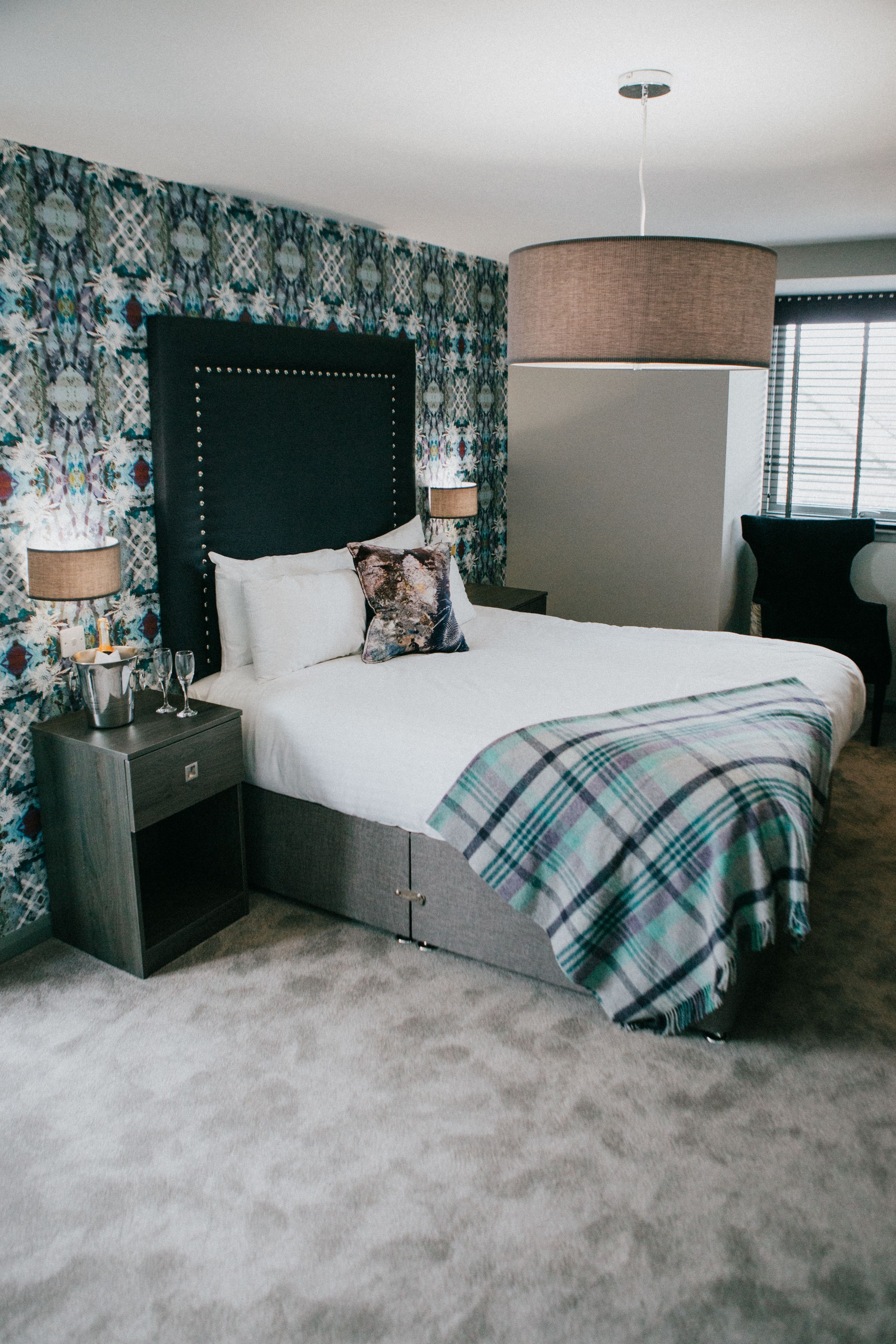 A neatly arranged bedroom with a bed, bedside tables, and a hanging lamp.
