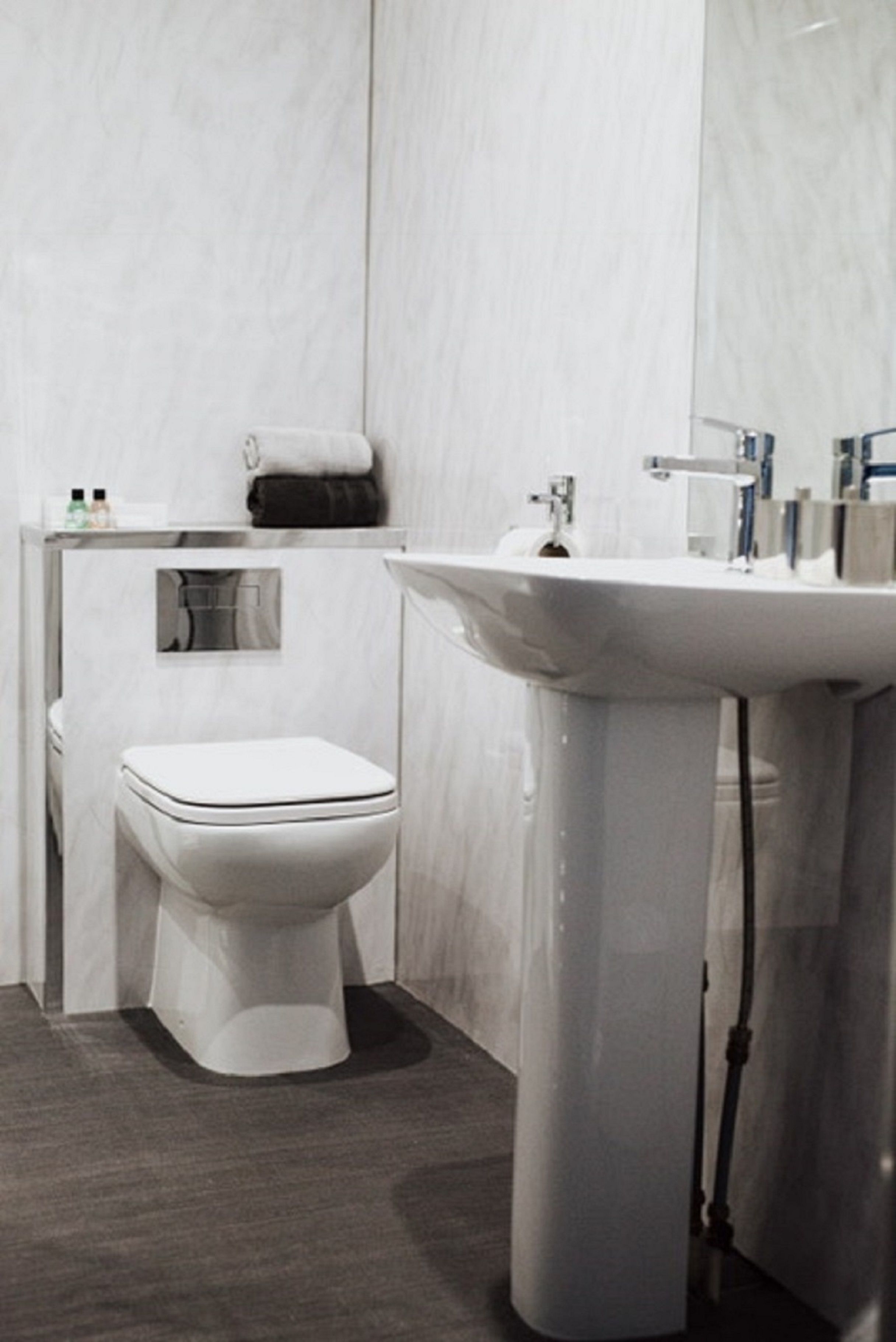 A modern bathroom with a white toilet, a sink, and a mirror.