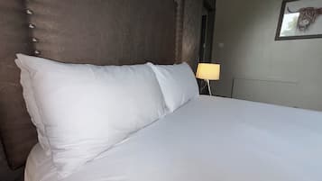 Una cama bien hecha con sábanas blancas y un cabecero con diseño capitonado.