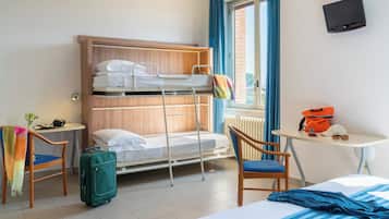 Una habitación de hotel con una cama litera, un escritorio, una silla, una maleta y un televisor.
