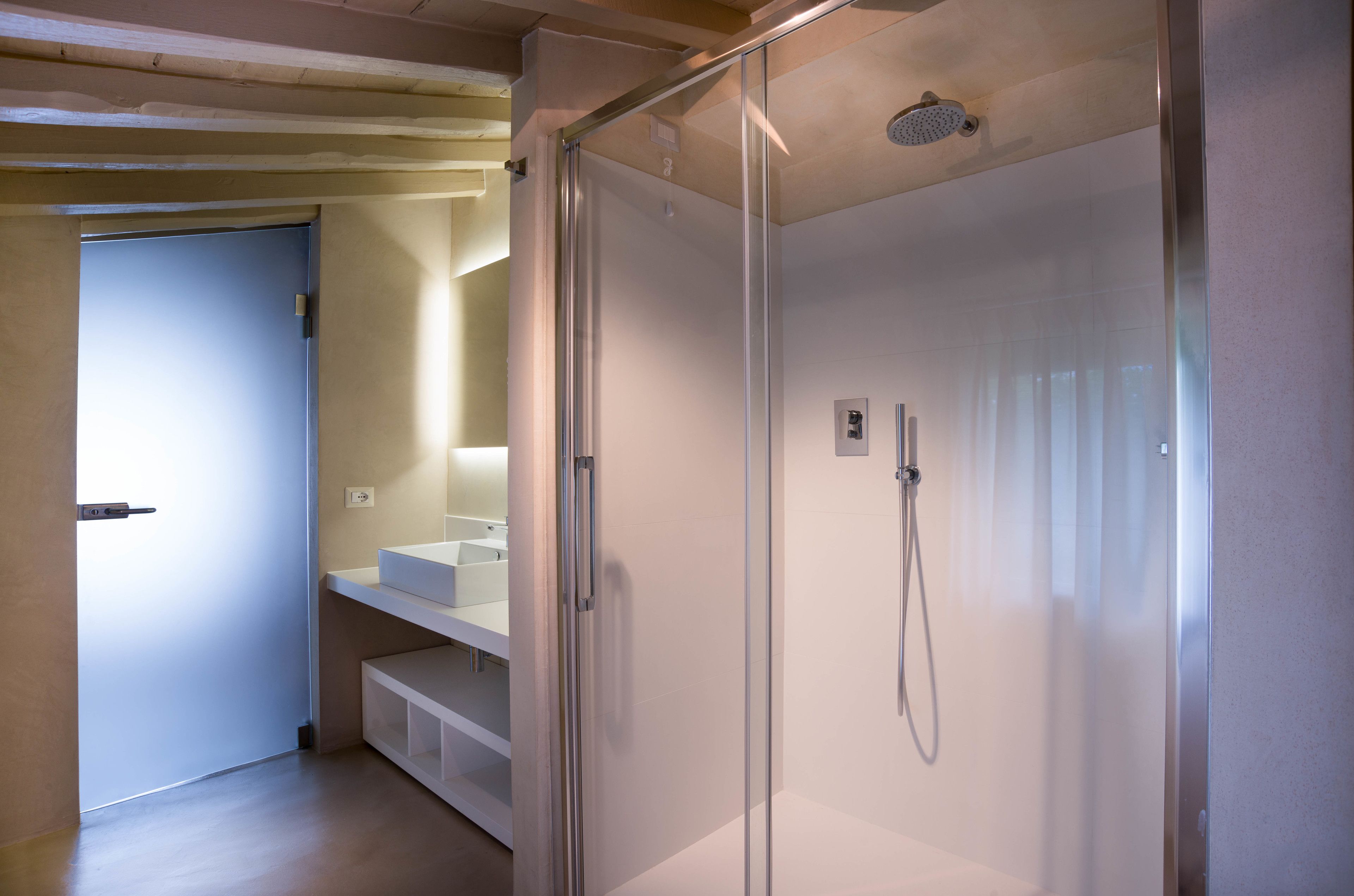 Uma casa de banho moderna com chuveiro de cabine de vidro, lavatório branco e banco embutido.