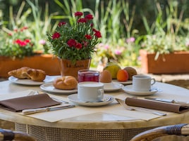 Una mesa de desayuno con cruasanes, huevos, un bol de fruta y una taza de café.