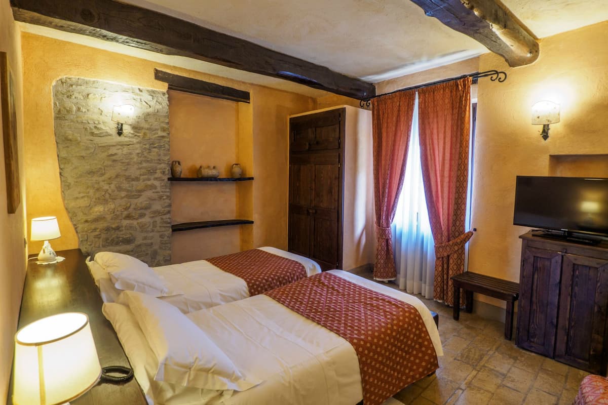 Ein gemütliches Hotelzimmer mit zwei Betten, einem Fernseher und einer Steinwand.