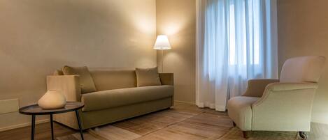 A modern living room with a sofa, armchair, and a small table with a lamp.