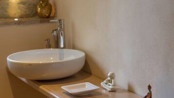 A bathroom with a white sink, a small white tray, and a Buddha statue.