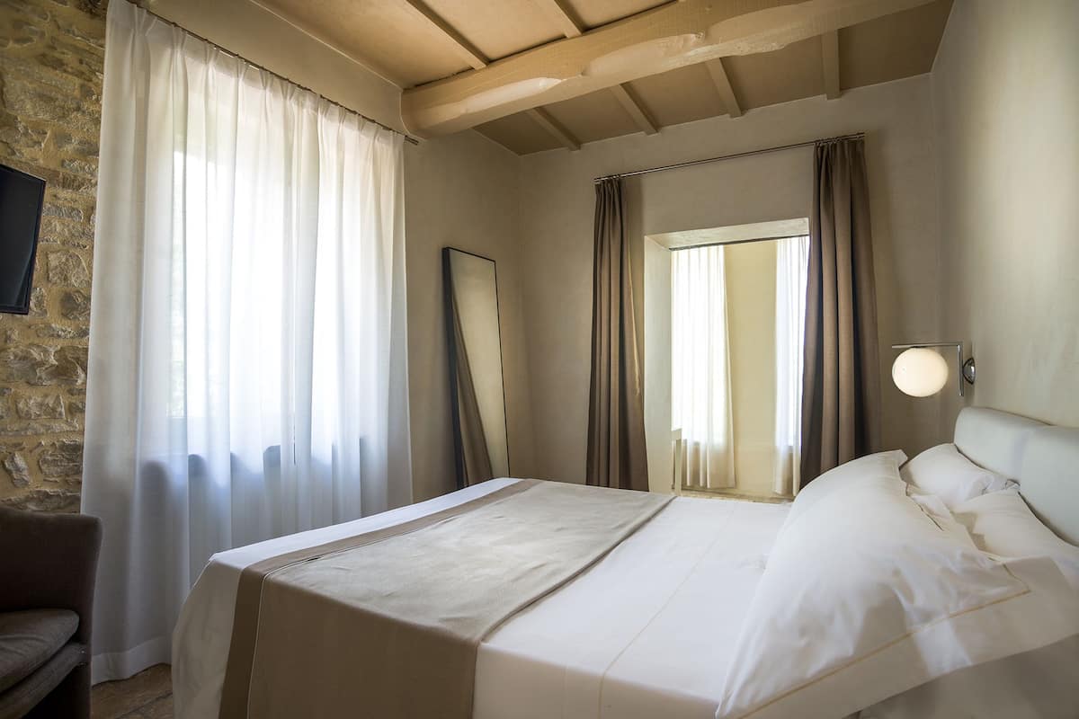 Ein Hotelzimmer mit einem Bett, einem Sessel, einem Spiegel und einer Wandlampe.