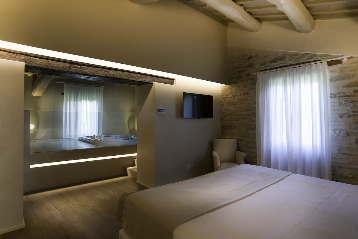 Ein modernes Hotelzimmer mit einem großen Bett, einem integrierten Schreibtisch, einem Flachbildfernseher, einer kleinen Sitzecke und einer Wand mit Steinakzenten.