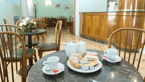 A dining area with a table set for tea, including a teapot, cups, and pastries. - Hotel San Pietro (Assisi)