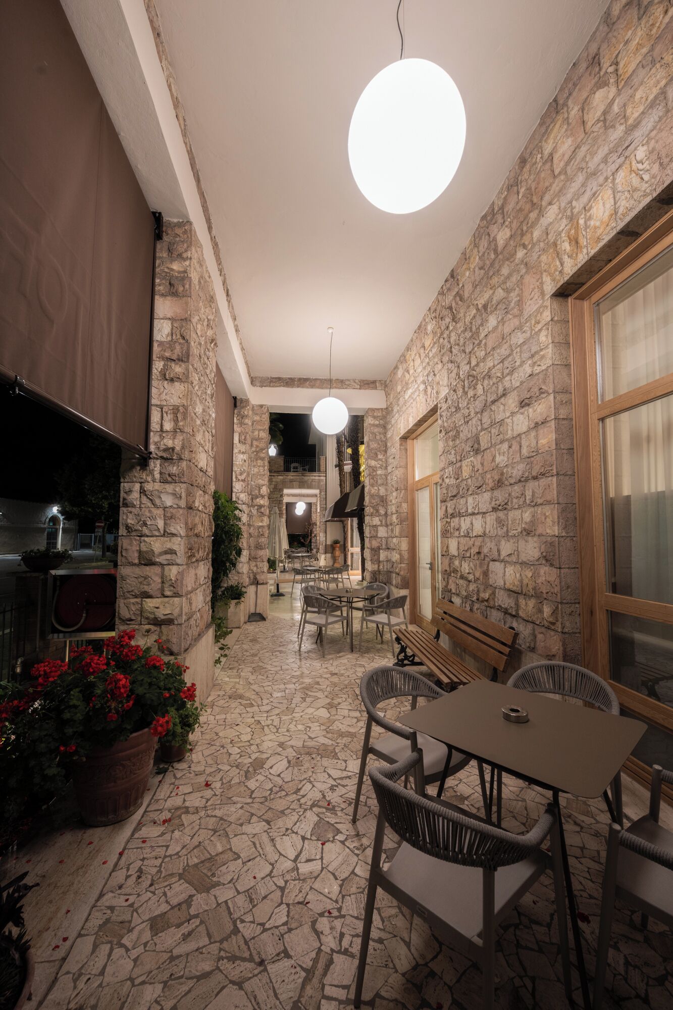 A stone-walled patio with outdoor seating, a hanging light, and a view into the interior.