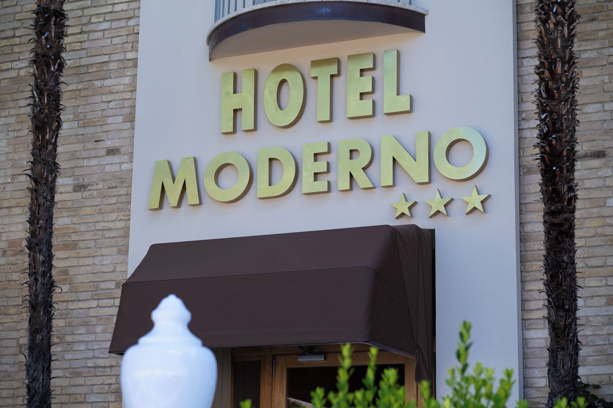 A building with a sign that reads "HOTEL MODERNO" and three stars.