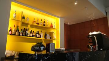 A bar area with shelves of liquor bottles, a coffee machine, and a marble countertop.