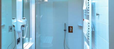 Un baño moderno con dos lavamanos, ducha con mampara de vidrio y un inodoro.