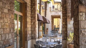 An outdoor patio with stone walls, a round table with chairs, and a hanging light fixture. - Hotel Moderno (Assisi)