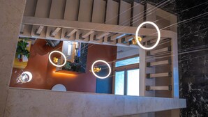 A modern interior with a staircase, circular light fixtures, and a marble wall. - Hotel Moderno (Assisi)