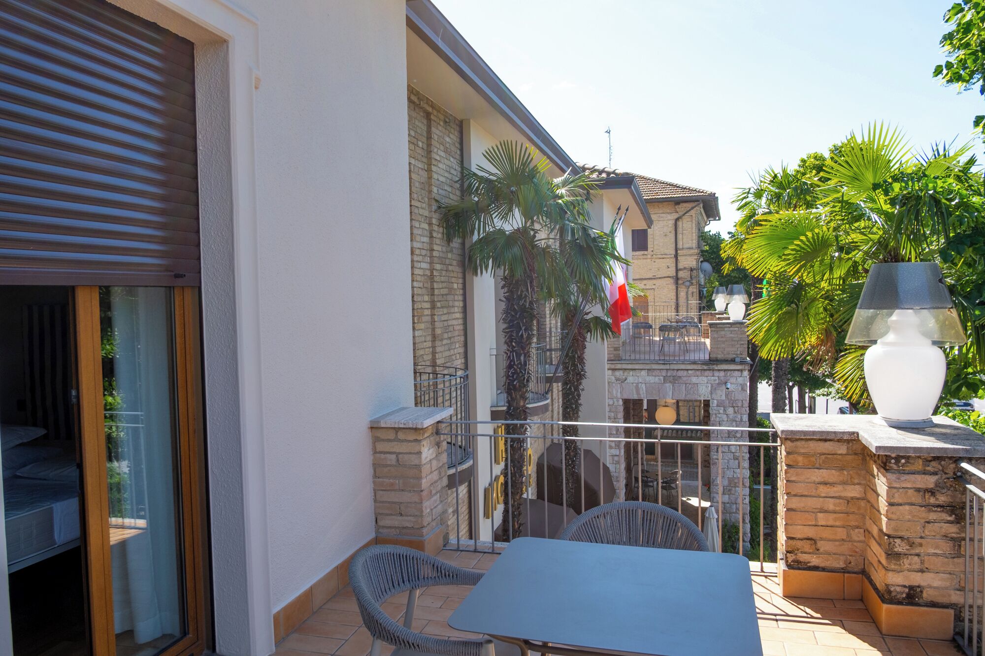 A balcony with a table and chairs, a flag, and a lamp.