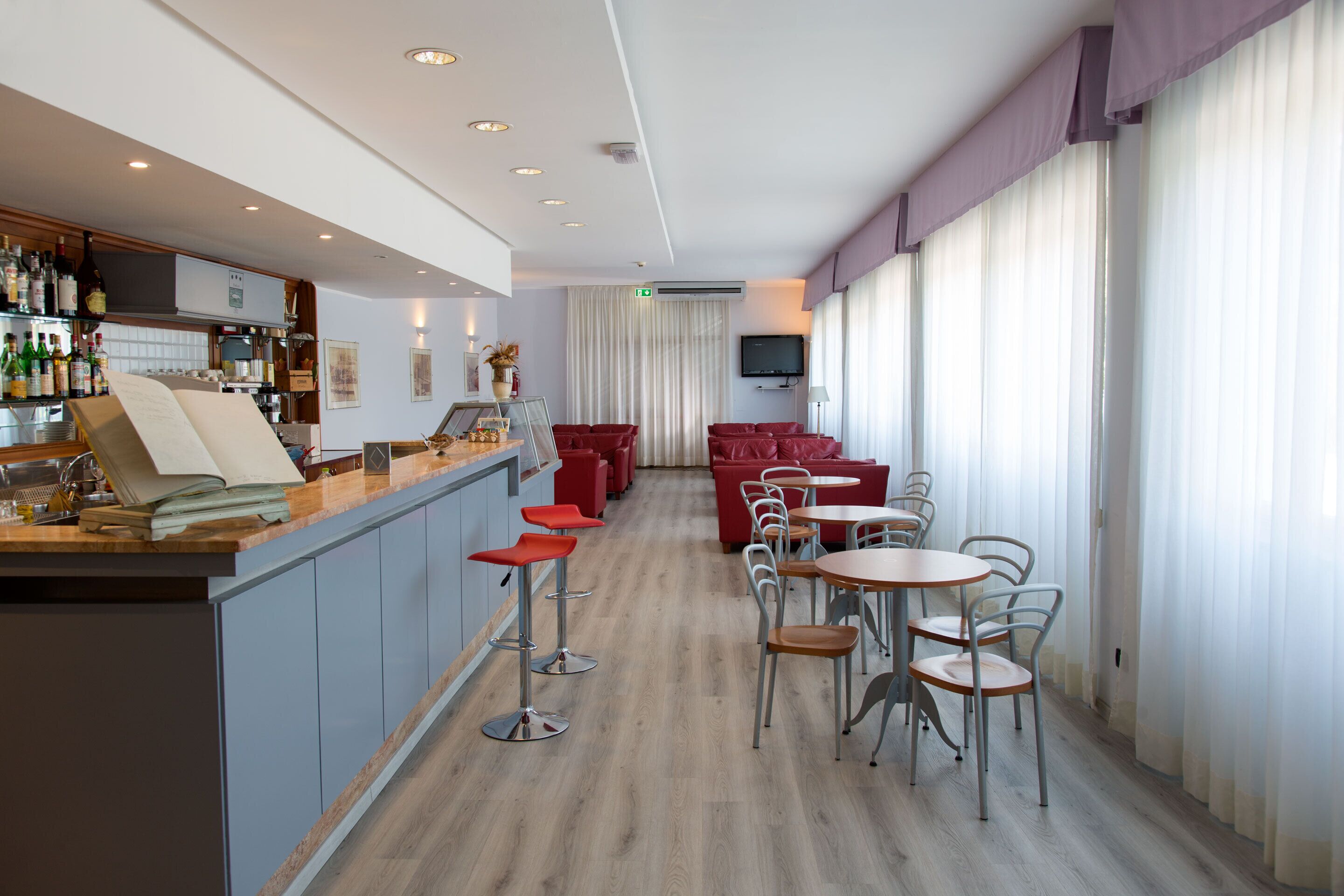 Eine moderne Hotelhalle mit Barbereich, Sitzgelegenheiten und einem Fernseher.